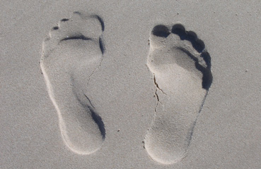 A picture of two footprints in the sand representing carbon footprints